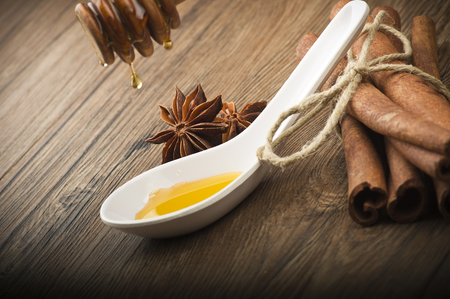 wooden honey dipper and spices on wood table の写真素材
