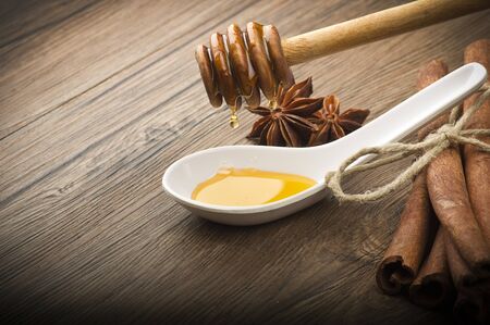 wooden honey dipper and spices on wood table の写真素材