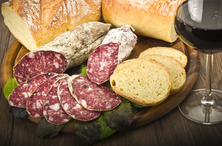 wooden cutting board with salami and glass of Red wineの写真素材