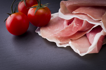 Raw ham leg sliced  with three tomatoesの写真素材