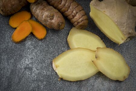 turmeric slices and ginger root sliced on gray backgroundの写真素材