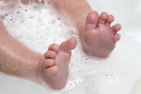 Baby feet wet and soapy in bathtubの写真素材
