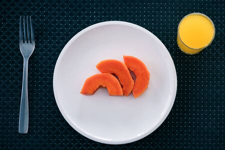 three pieces of papaya serve with orange juicesの写真素材