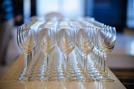 many empty wine glasses line up waiting for pouring some liquor for many invitation guest in dinner reception celebration party in a lounge in the hotelの写真素材