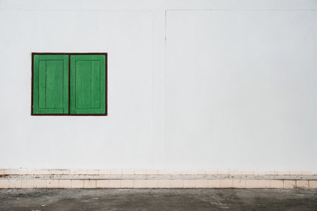 green wood window frame on white wall by walkwayの写真素材