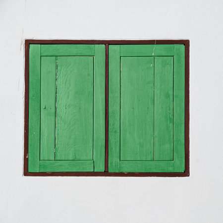 green wood window frame on white wall by walkwayの写真素材