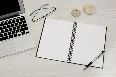 blank page of notebook on table with glasses and laptopの写真素材