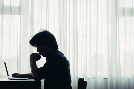a stressed man feeling unhappy sitting with his laptop in a  small roomの写真素材