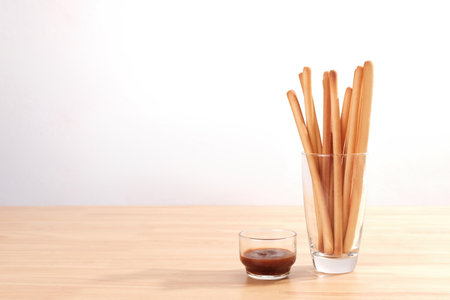 breadsticks in transparent glass with ketchup on wooden tableの写真素材