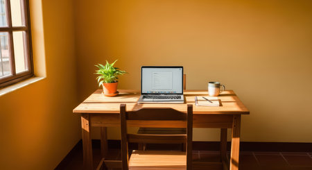 Cozy minimalist workspace with laptop and plant on wooden desk by sunlit windowの素材