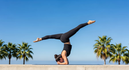 Asian female performing yoga headstand outdoors in tropical settingの素材