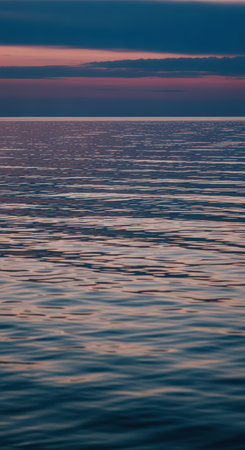 Serene ocean at sunset with calm waves and pink sky reflectionsの素材