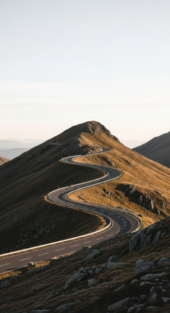 Winding mountain road under clear sky: serene landscape with curving highwayの素材