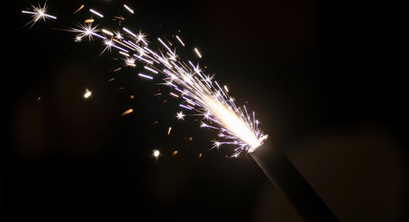 Sparkler illuminating dark background with bright shimmering sparksの素材