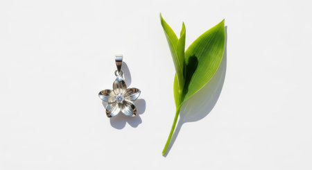Elegant flower-shaped silver pendant with zircon stone and green leaf on white backgroundの素材