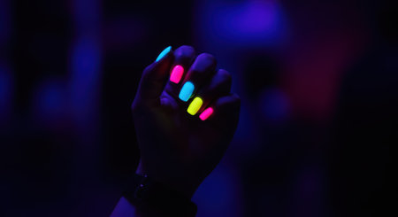 Neon painted nails glowing in dark lightの素材