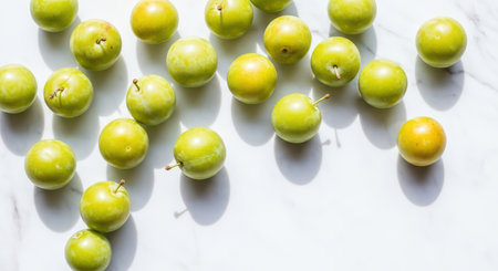 Fresh green plums on white marble surface in natural lightの素材