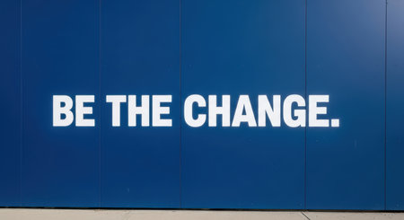 Inspirational message 'be the change' on blue wall encouraging positive actionの素材