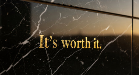 Golden inspirational quote on black marble surface in natural lightの素材