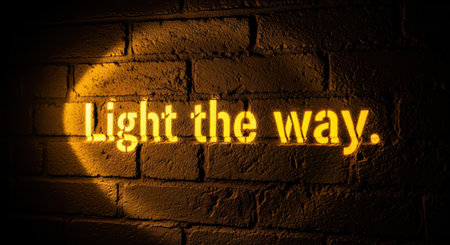 Glowing text on brick wall with inspiring message at nightの素材