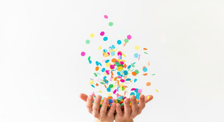 Colorful confetti falling into open hands against white backgroundの素材