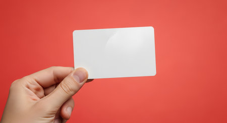 Hand holding blank card on red backgroundの素材