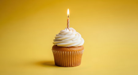 Vanilla cupcake with lit candle on yellow backgroundの素材