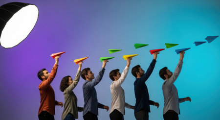 Diverse adults launching colorful paper planes in creative office settingの素材