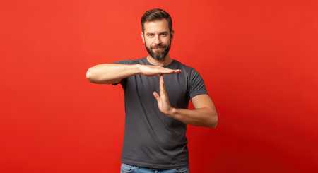 Caucasian male adult gesturing time out against red backgroundの素材