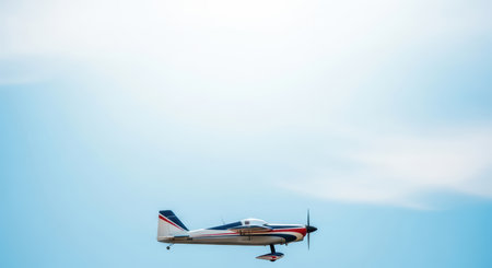 Small airplane flying under clear blue skyの素材
