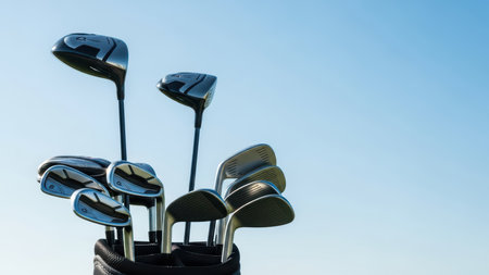 Collection of golf clubs in bag against clear blue sky.の素材