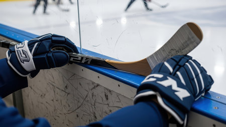 Hockey player with stick and gloves on ice rink.の素材