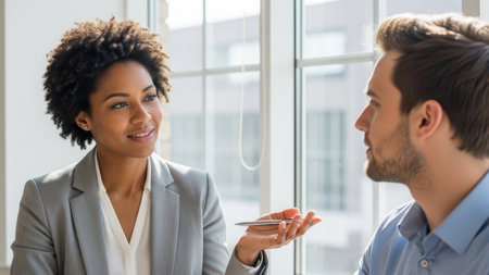 Professional discussion between young african female and caucasian male colleagues in office.の素材