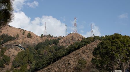 Telephone towers set up on the top of a hill with jungle at the base.の写真素材