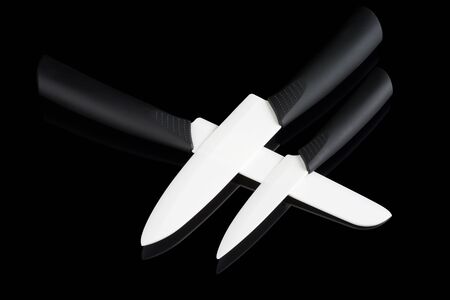 Set of three white ceramic knives on black reflecting backgroundの写真素材