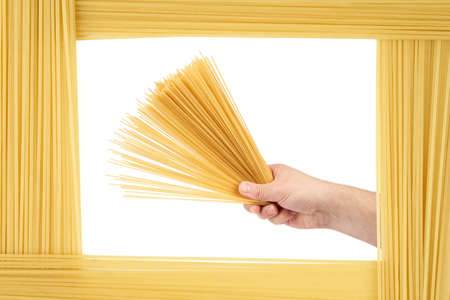 Man holds raw pasta (capellini). The frame is made of the same pasta (capellini).