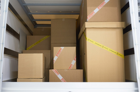 View of the cargo area of light commercial vehicle. Russian text on yellow adhesive tape of the box:...