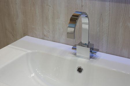 Moderm metal shiny mixer mounted on white ceramic washbasinの写真素材