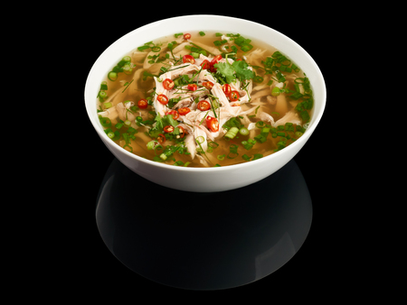 Plate of vietnamese chicken noodle soup Pho Ga isolated on black reflecting background