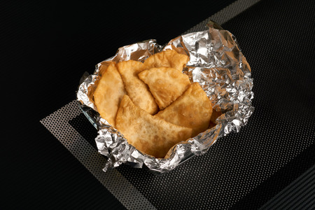Chebureks on dark background. Cheburek is a caucasian food, a patty made from thin unleavened dough...