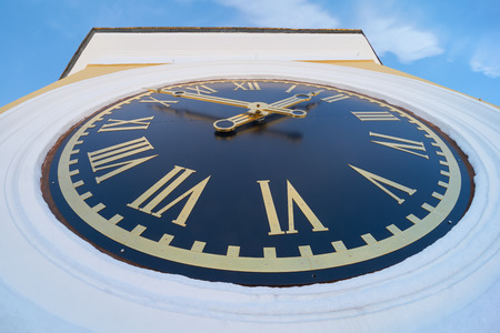 Turret clock with roman numerals on blue clock face. Bell tower of the Epiphany Cathedral in the...