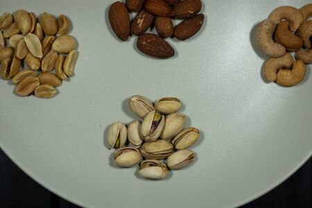 Different kinds of nuts in white dish top view Almonds, Pistachios, Cashews, peanut, hazelnut, Dry...