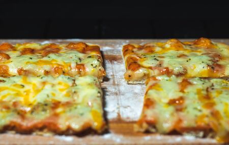 Flat bread pizza by cheese on a cutting board with flour in black backgroundの写真素材