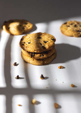 Chocolate chip cookies and crumbs on white background under the sunshine in front of the window