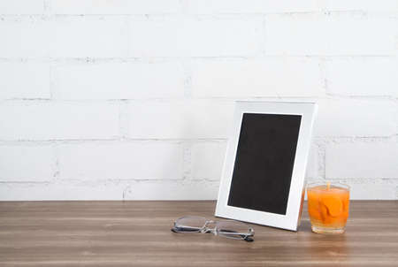 Silver freestanding photo frame on bedside table accompanied by a scented mandarin candle