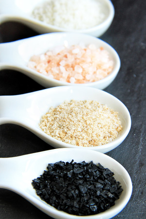 Variety of Different Sea Salts in spoons on a black slate stone backgroundの写真素材