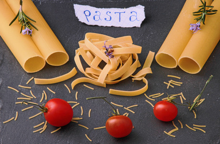 Variety of Pasta and tomatos on a black slate