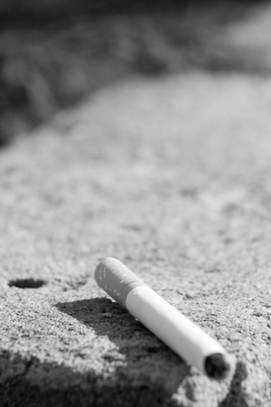 Black and white photo of a cigarette lying on concreteの写真素材
