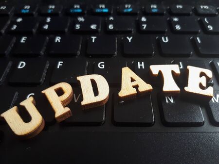 The word 'update' made of wooden letters. wood inscription on keyboard backgroundの写真素材