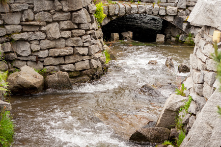 A mountain stream flowing between a stone wallの写真素材